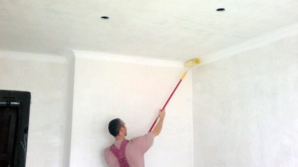 A man primers the ceiling