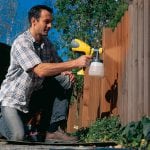 Painting a fence with a spray gun