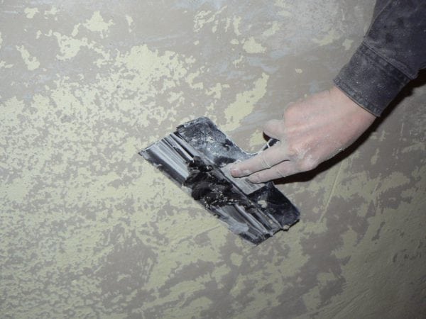 Cleaning the wall with a spatula before painting