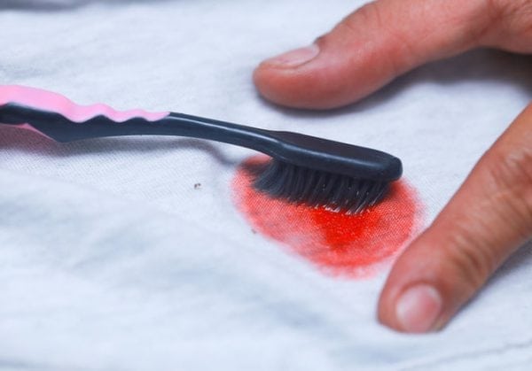 Removing paint from clothing with a toothbrush and stain remover